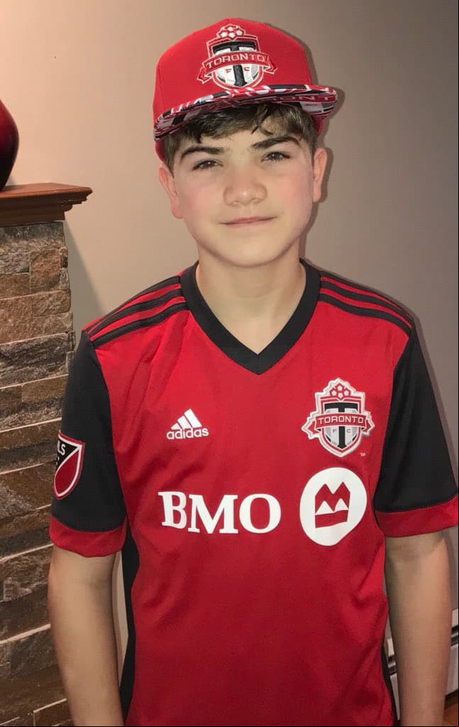 Un joven adicionado del campeón Toronto FC, vistiendo con estilo la playera y la gorra Escarlata.